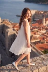 Plisseekleid Rozalia in Weiß – Seitenansicht vor der Stadtmauer